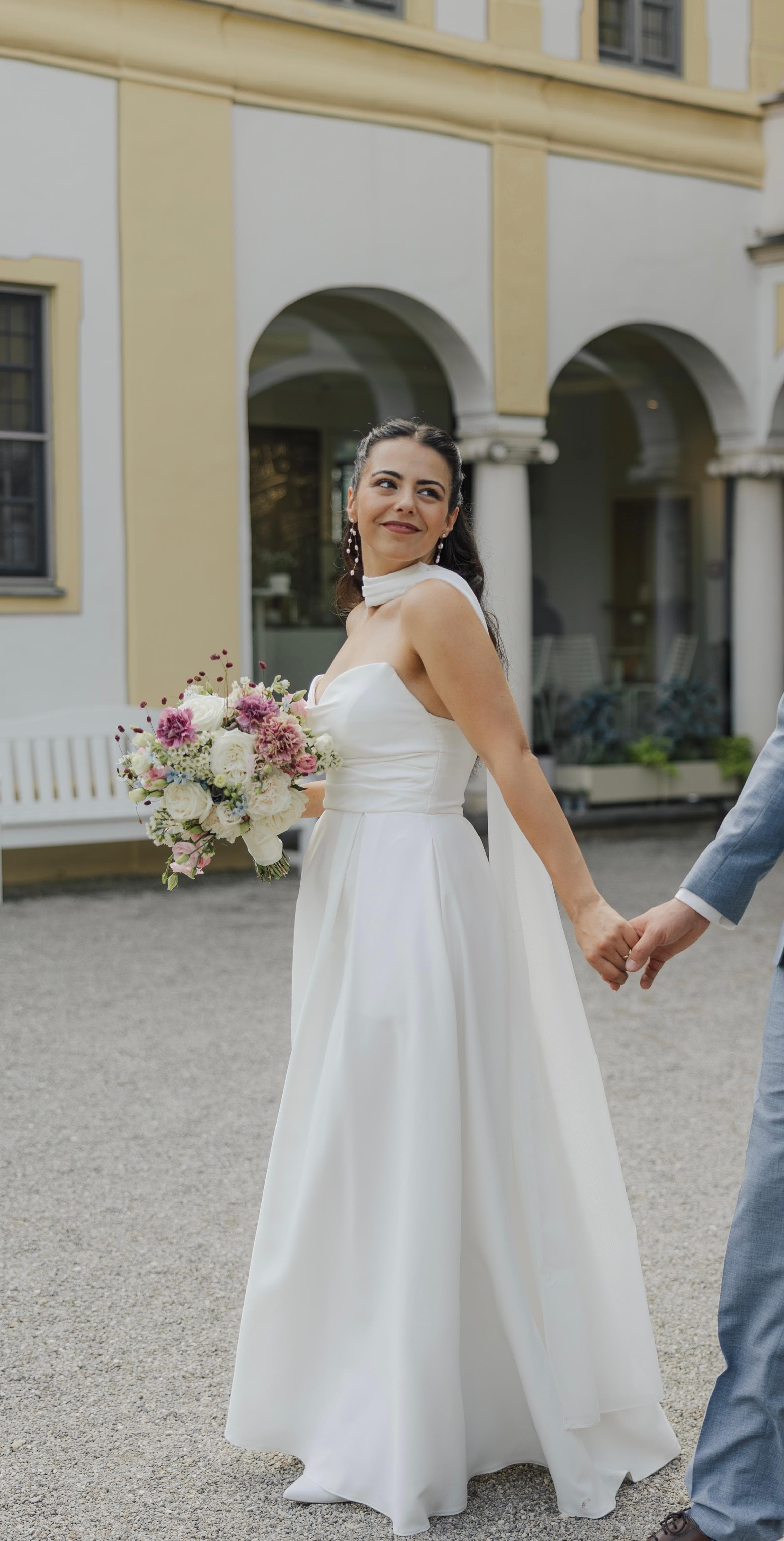 Braut mit Brautstrauß vor dem Schloss – Brautstyling von Natascha Sedlmair